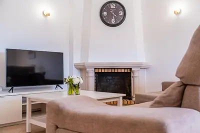 a living room with a fireplace and a clock on the wall at Villa Lamella in Albufeira