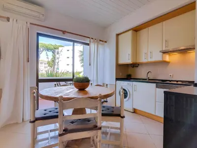a kitchen with a wooden table and a table at Apartamento Alvaflor com Piscina – Vilamoura in Quarteira
