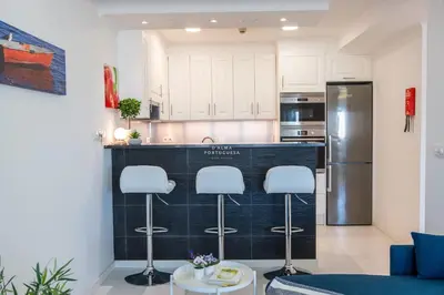 a kitchen with white cabinets and a black counter top at Downtown Studio - By D`alma Portuguesa in Albufeira
