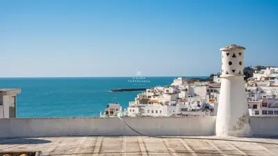 a lighthouse on the side of a town with the ocean at Downtown Studio - By D`alma Portuguesa in Albufeira
