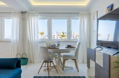 a living room with a table and chairs and windows at Downtown Studio - By D`alma Portuguesa in Albufeira