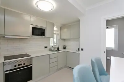 a kitchen with white cabinets and a blue chair at Monte Verde C - CD 295, Cleverdetails, Sleeps 2 adults and 2 children, 4 salted water pools in Vilamoura
