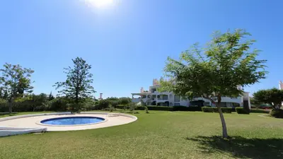 a tree in a yard with a building in the background at Monte Verde C - CD 295, Cleverdetails, Sleeps 2 adults and 2 children, 4 salted water pools in Vilamoura