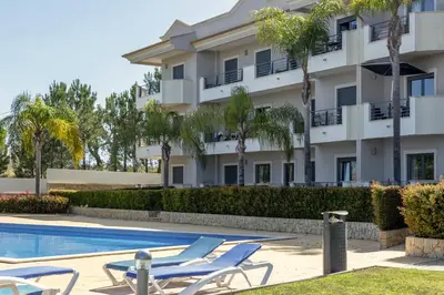 a hotel with lounge chairs next to a swimming pool at Moradia Flaj in Olhos de Água