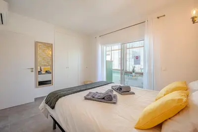 a bedroom with a bed with yellow pillows and a window at Albufeira Old Town Sea View Apartment in Albufeira