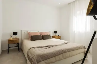 a white bedroom with a large bed with pink pillows at The Marina Collection in Quarteira