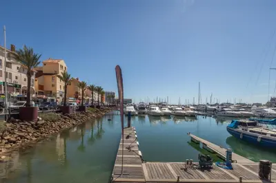 a dock with boats in a marina with buildings at The Marina Collection in Quarteira