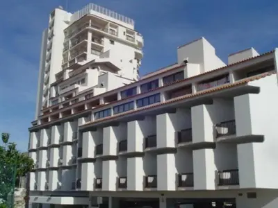 a large white building in front of a tall building at Apartamento Ariadna in Albufeira