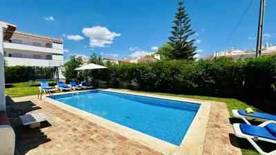 a swimming pool in a yard with blue lounge chairs at Strip II by Check-in Portugal in Albufeira