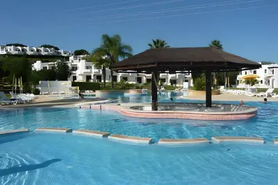 a swimming pool with an umbrella in a resort at Villa Rose in Albufeira