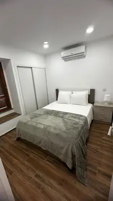 a bedroom with a large white bed and wooden floors at Albufeira Oura Apartment II in Albufeira