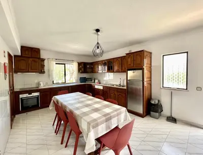 a kitchen with a table with chairs and a refrigerator at Vivenda Duas Sentinelas 42 in Quarteira