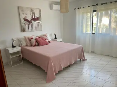 a bedroom with a pink bed and a window at Vivenda Duas Sentinelas 42 in Quarteira