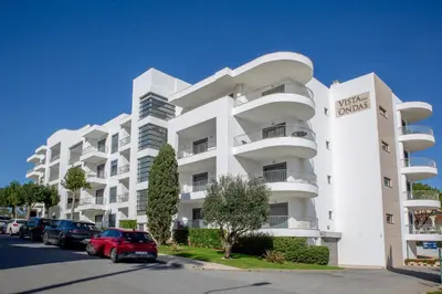 a white apartment building with a red car parked in front at Casa do sol in Olhos de Água