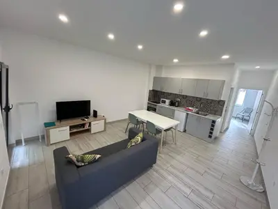 a living room with a couch and a table and a kitchen at Casa Jonhy in Faro