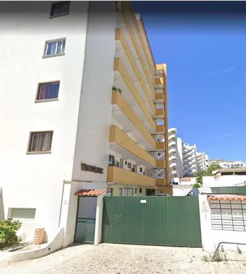 a white building with a green gate in front of it at SMILE Apartment Albufeira in Albufeira