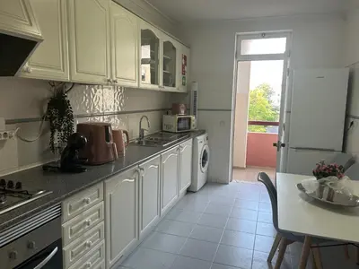 a kitchen with white cabinets and a white refrigerator at Penha House II in Faro
