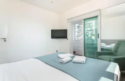 a white bedroom with a bed and a chair at Blife Charlya private apartment at Faro beach in Faro