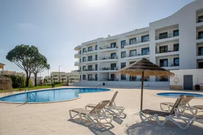 a hotel with chairs and an umbrella and a pool at Luz do Mar in Olhos de Água