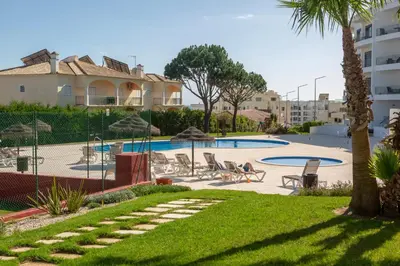 a resort with a swimming pool and palm trees at Luz do Mar in Olhos de Água