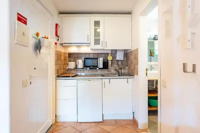 a kitchen with white cabinets and a microwave at Charming Yellow Studio in Albufeira in Olhos de Água