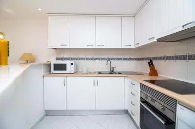 a kitchen with white cabinets and a sink and a microwave at Downtown Apartment - By D`alma Portuguesa in Albufeira