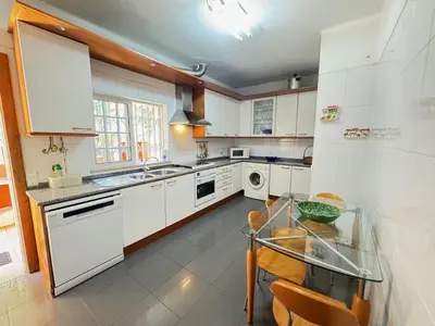 a kitchen with white cabinets and a glass table at Palm Villa in Albufeira
