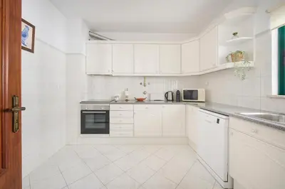 a white kitchen with white cabinets and a sink at 2 Bedroom by Quarteira Beach in Quarteira