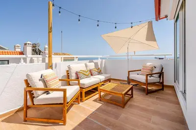 a balcony with chairs and a table and an umbrella at Sandora Pearl By Seareen, Penthouse with sea view in Albufeira