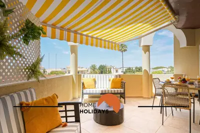 a patio with a yellow and white striped awning at #283 Palmeira Gale by Home Holidays in Galé