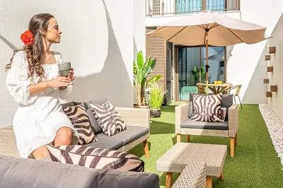 a woman sitting on a couch with a drink at Downtown Luxury Studio - Faro in Faro