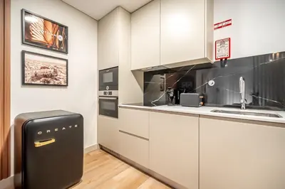 a kitchen with white cabinets and a black refrigerator at Downtown Luxury Studio - Faro in Faro
