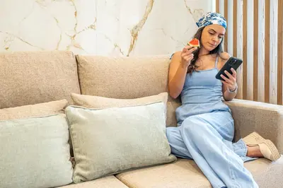 a woman sitting on a couch looking at her cell phone at Downtown Luxury Studio - Faro in Faro
