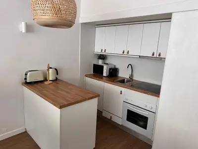 a kitchen with white cabinets and a wooden counter top at Vilamoura Living 106 in Quarteira