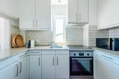 a white kitchen with white cabinets and a sink at Vale do Lobo Apartment D in Vale do Lobo