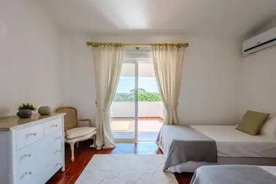 a bedroom with two beds and a sliding glass door at Vale do Lobo Apartment D in Vale do Lobo