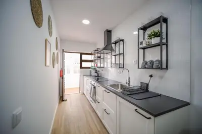 a white kitchen with a sink and a counter at Apartamento JADA in Albufeira