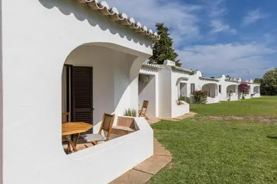 a white house with a table and chairs in the yard at Albufeira Club 109 in Albufeira