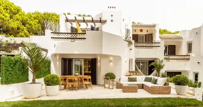 a white house with a patio with a table and chairs at Luxury Garden House Apartment - Golf & Tennis Court & Pools in Albufeira