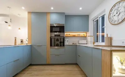 a kitchen with blue cabinets and a large clock on the wall at Luxury Garden House Apartment - Golf & Tennis Court & Pools in Albufeira