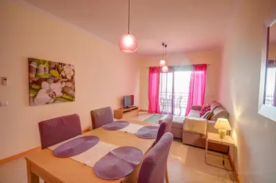 a living room with a table and chairs and a couch at Apartament Encosta Da Orada in Albufeira