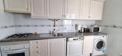 a kitchen with white cabinets and a stove and a sink at Manu's Place in Albufeira