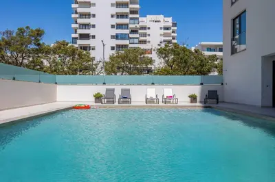 a swimming pool with chairs and a building at Terracos de Quarteira I Aqua by Real Properties in Quarteira