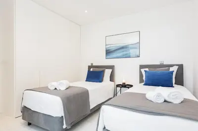 two beds in a white room with blue pillows at Terraccos de Quarteira Silver by Real Properies in Quarteira