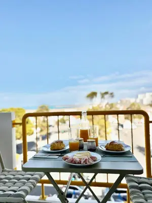 a table with plates of food on a balcony with the beach at Casa do Largo - Quarteira Algarve in Quarteira