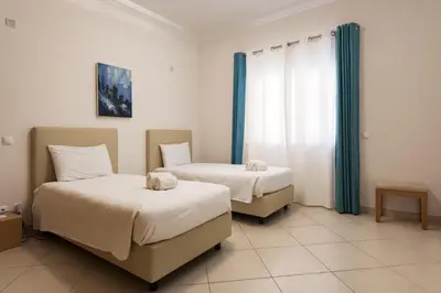 two beds in a room with blue curtains at Praia Village III - Peaceful condominium by HD in Quarteira
