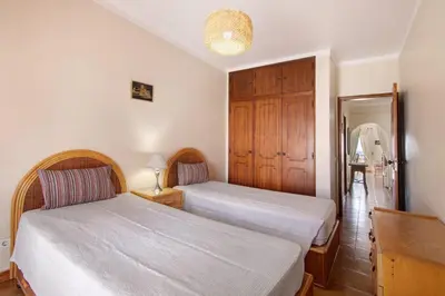 a bedroom with two beds and a wooden cabinet at Beachfront Apartment T2 in Quarteira