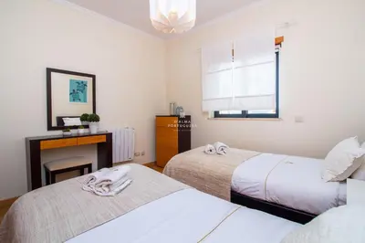 a bedroom with two beds and a desk and a window at Rosemary Apartment in Olhos de Água