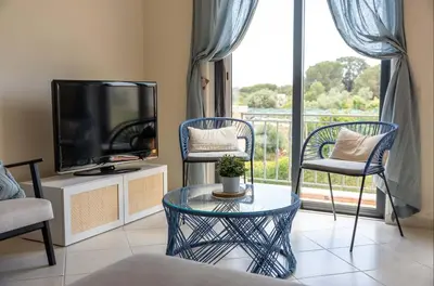 a living room with a tv and two chairs and a table at Rosemary Apartment in Olhos de Água