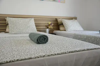 two beds with a green pillow on top of them at Train Station Guesthouse in Faro